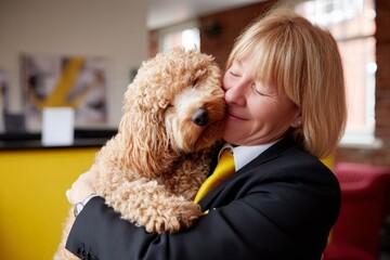 Obraz na płótnie Canvas Woman embracing fluffy dog in a bright modern office