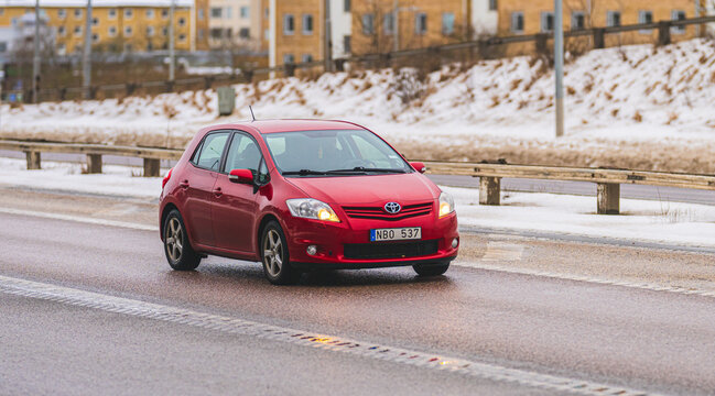Gothenburg, Sweden - February 22 2026: Red Toyota Auris compact hatchback driving on snowy urban road in winter.