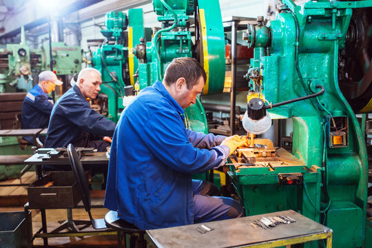 Worker in production plant drilling at machine on the factory floor. Factory Workers at Work. Workers operating metal processing machines at workshop.