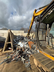 Fototapeta premium Steel cuttings in a scrap yard with crane waiting to load trucks with dramatic sky