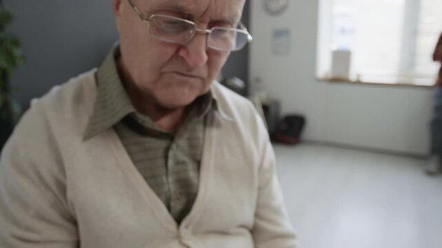 Close up of senior Caucasian man wearing eyeglasses holding clipboard and pen filling in hospital check in form at reception area
