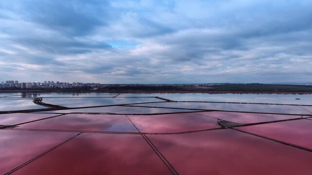 Thick clouds covered the sky over the pink salty lakes. Modern industry for salt extraction from drone footage.