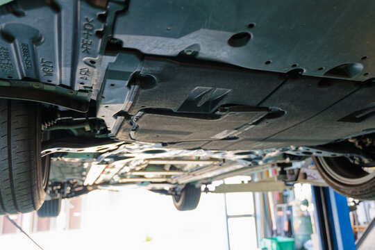 Underside of a passenger car lifted in an auto repair shop for vehicle inspection and maintenance