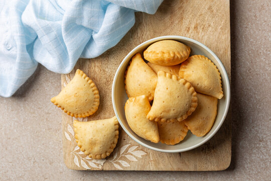Plate with just Baked empanadas, pasty or panzerotti is a type of baked  turnover pastry and filling, common in Spain, Portugal, Italy,  Latin Amirican countries. Filling  cheese and tomato. Top view.