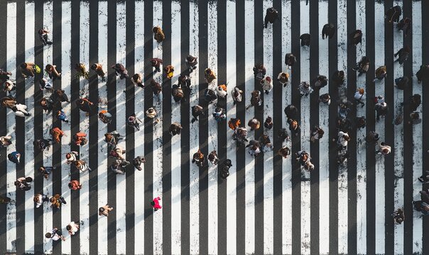Aerial view of a bustling pedestrian crossing with numerous people walking across the zebra stripes in a city.