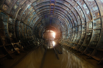 Fototapeta premium Flooded dark abandoned rusty underground subway construction tunnel