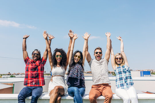Friends celebrating on rooftop with raised hands