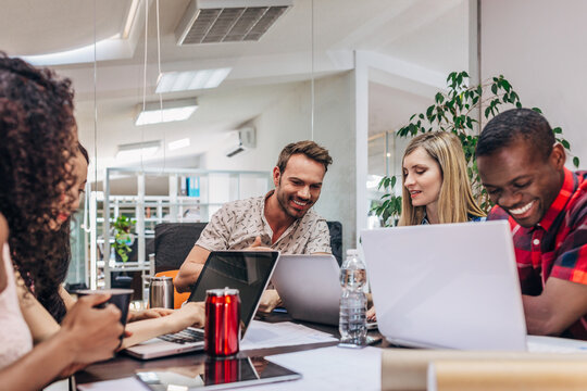 Diverse team collaborating with laptops in modern office