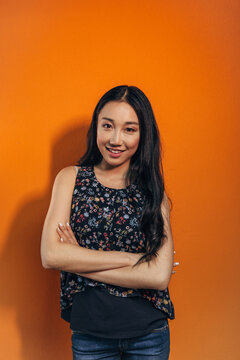Confident young woman portrait on orange studio background