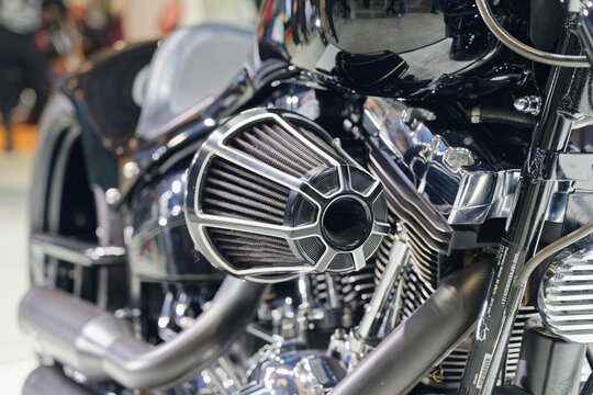 Close-up of a custom motorcycle engine and air intake at an indoor motorcycle exhibition