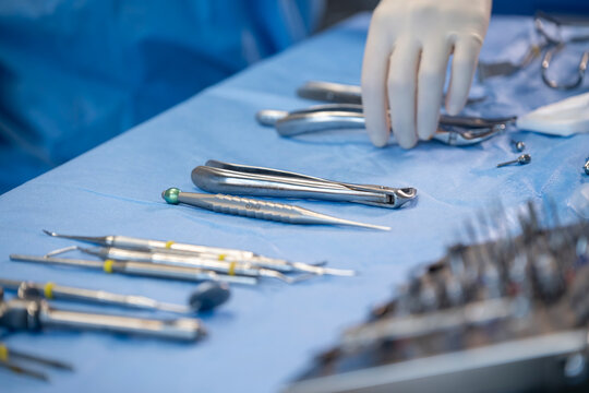 Instruments dentaires st&eacute;riles sur table de soin avec main de praticien en gants