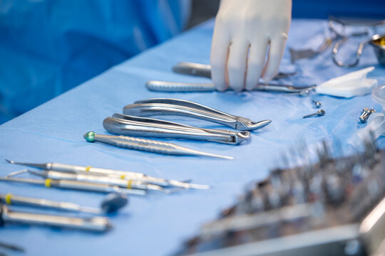 Instruments dentaires st&eacute;riles sur table de soin avec main de praticien en gants