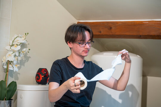 Jeune homme tenant du papier toilette dans une salle de bain &agrave; domicile