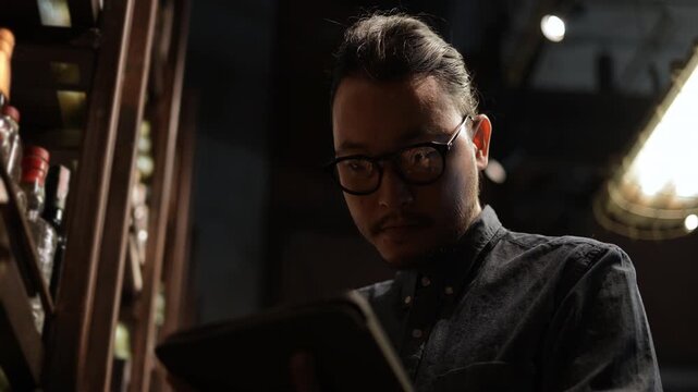 Night club concept of 4k Resolution. Asian man checking the stock of liquor on the shelf.