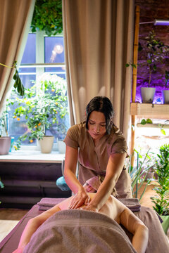 Professional lady masseuse making healing full body massage for woman client in spa salon. Female receiving beauty treatment for stress and pain relief, therapist massaging and relaxing back muscles.