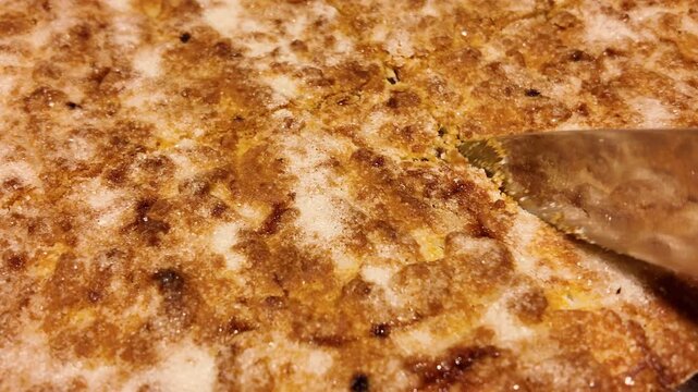 Freshly baked shortbread pie is cut into portions with a knife