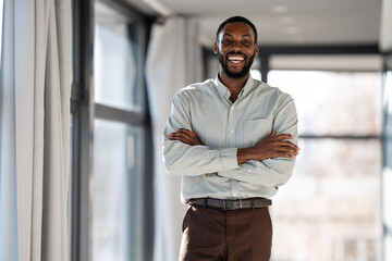 Obraz premium Confident african american businessman smiling with arms crossed