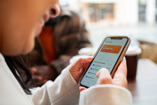 Person using mobile banking app at coffee shop table