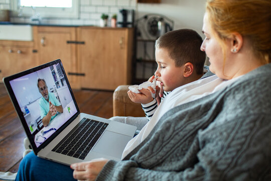 Mother comforting sick son during telehealth video consultation at home