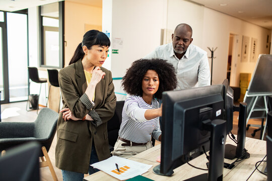 Diverse coworkers collaborating at desktop computers in modern office