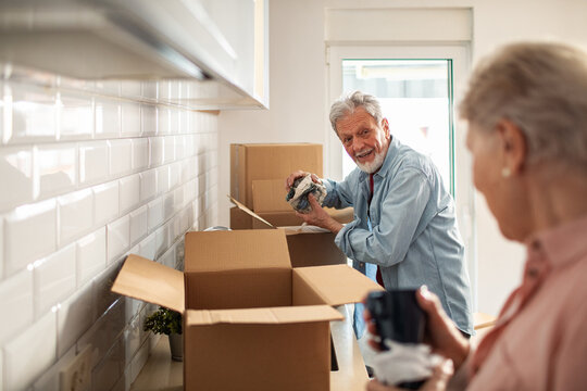 Senior couple unpacking moving boxes in kitchen