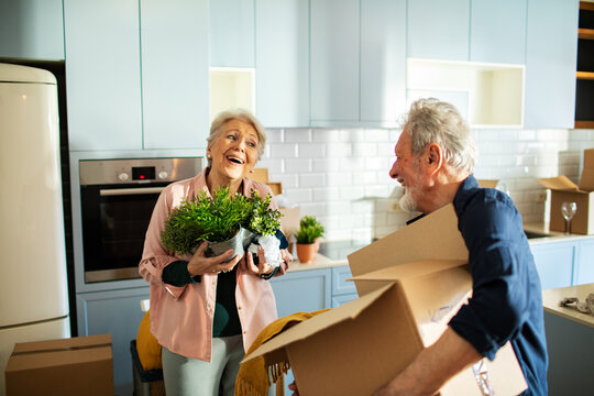 Smiling senior couple unpacking boxes in new kitchen