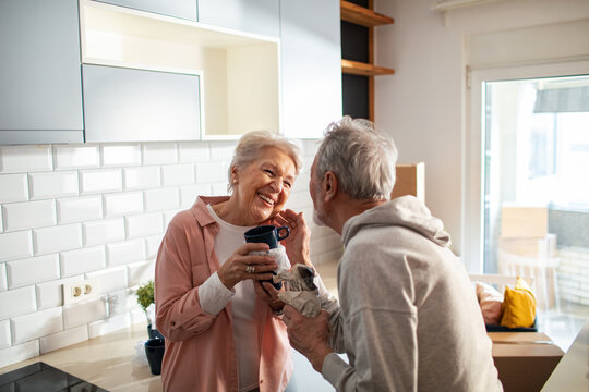 Happy senior couple unpacking mugs in new kitchen