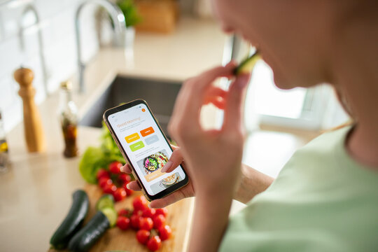 Woman using meal planning app in home kitchen