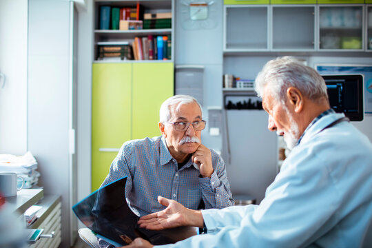Elderly man discussing x-ray results with doctor in medical office