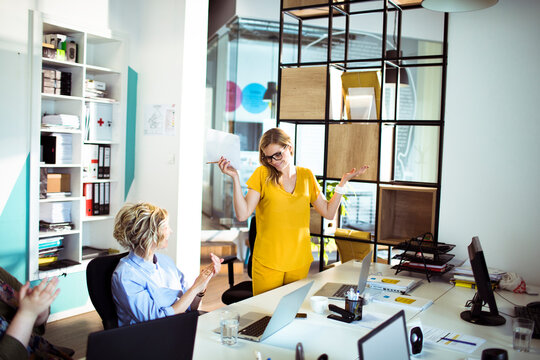 Coworkers applauding female colleague in modern office