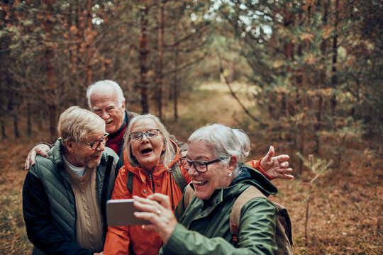 Happy senior friends taking a hiking selfie in the forest