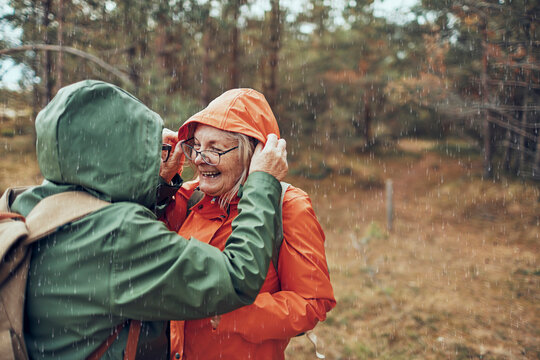 Senior couple laughing in the rain during forest hike