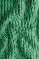 Close up, macro of crumpled green colored knitted fabric. Cloth with visible wrinkles, folds and soft waves. Soft wool material texture with detailed stitches and creases, textile background © katyamaximenko
