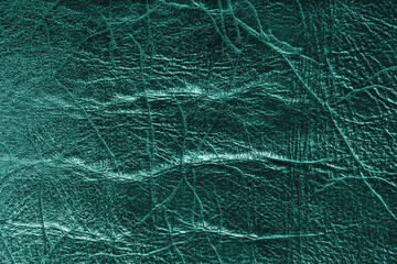 Fototapeta premium Detailed close up, macro of turquoise glossy metallic effect leather surface with visible wrinkles, creases and natural grain. Textured luxury material background, upholstery and design backdrop.