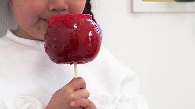 りんご飴を食べている女の子のイメージ（5歳、日本人）