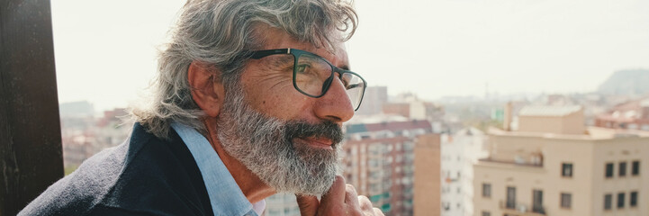 Obraz premium Senier enjoys the view standing on the balcony. Panoramic