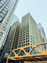 Naklejka premium Buildings and yellow bridge seen from ground level in a city on a cloudy day