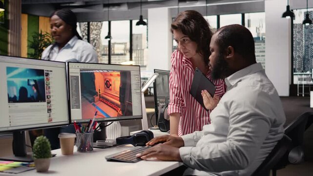 Game developers working on futuristic video game on computer, diverse team uses programming tools and software to design virtual world with spaceships and stations. Assets for gaming industry.