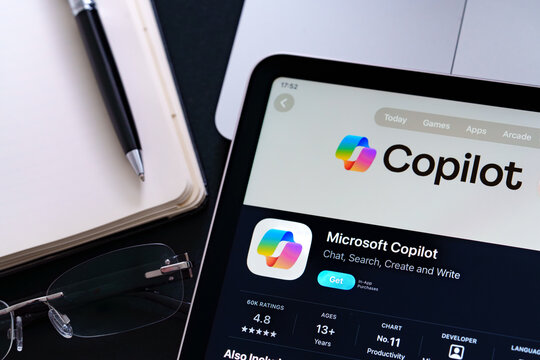 Microsoft Copilot listing on iPad highlights Apple Liquid Glass updated design and iOS 26 look in office desk scene. Stafford, United Kingdom, April 13, 2026.