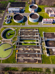 Naklejka premium Wastewater treatment facility located in a rural area showing various tanks, machinery, and green land in the daytime