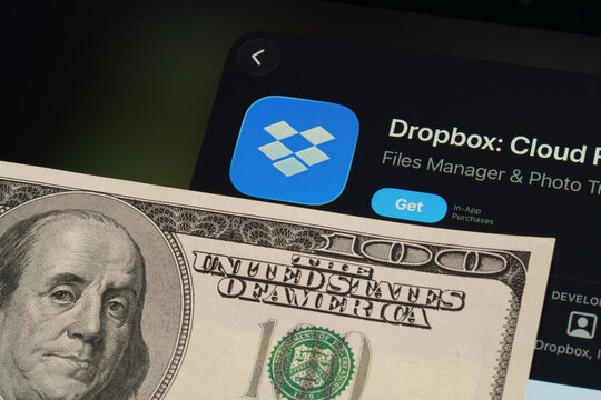 Dropbox logo and App Store page on iPad in Apple Liquid Glass iOS 26 design beside US dollar note. Stafford, United Kingdom, April 13, 2026.