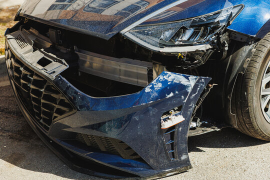 Car with damaged front end is parked on street near buildings in a city during daylight