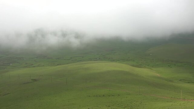 Time lapse clouds drift above treeless hill grasslands covered with vivid green summer growth. Moving sky reveals rolling plains open terrain natural rhythm across remote russian land.