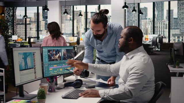 Videographers editing video footage on computer in creative agency, process of cutting and adjusting color grading on software with sliders. Diverse team working in movie post production.