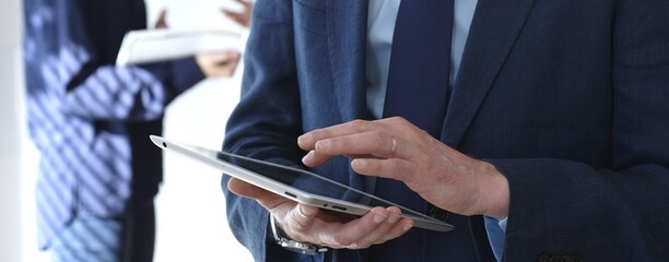 Businessman in a blue suit using a tablet during a corporate meeting, interacting with the...