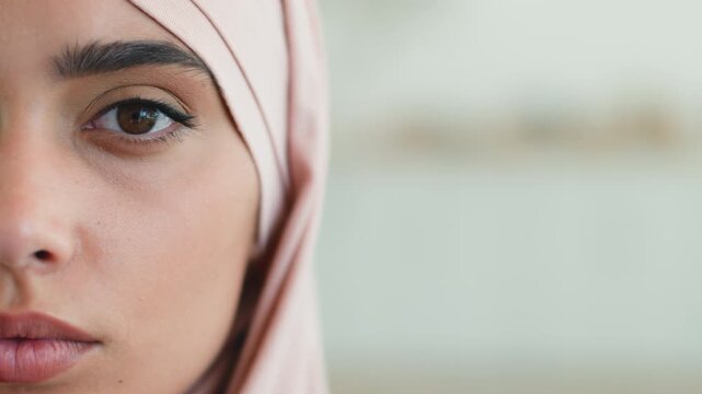 Close up pensive serious Muslim woman in hijab at home female Islamic girl portrait half face looking at camera thoughtful peaceful Arabian lady headscarf concern focused young adult reflective indoor