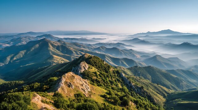 Rolling Green Mountains with Foggy Valleys Under a Clear Blue Sky landscape nature photo