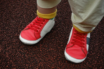Close up of toddler feet in red sneakers on track.