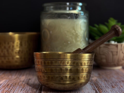 Brass Singing Bowl with Wooden Mallet on Rustic Table Symbolizing Meditation Sound Healing Mindfulness and Relaxation with Warm Lighting and Natural Wellness Spa Background