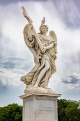 Obraz premium Angel statue holding cross with bird perched on head